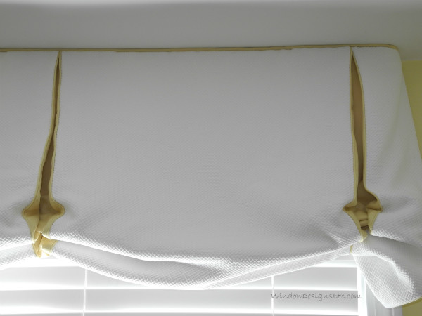 Detail of valance is a variation of a balloon and relaxed Roman shade in white matelasse with contrasting yellow in the pleats.